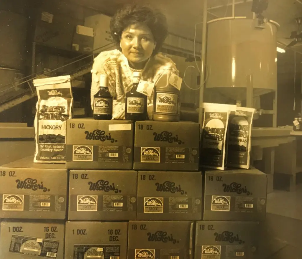 Woman leaning over boxes filled with Wicker's BBQ Sauce
